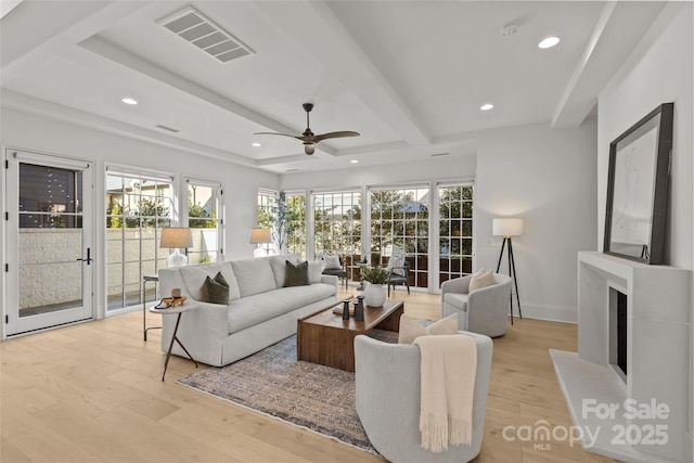 living room with ceiling fan, light hardwood / wood-style floors, and beamed ceiling