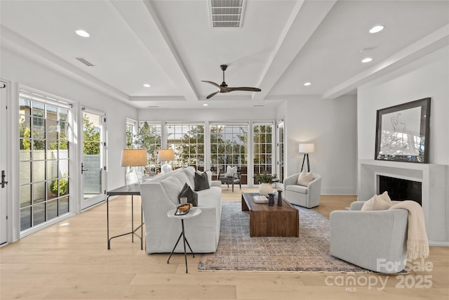 living room featuring ceiling fan, light hardwood / wood-style floors, and beam ceiling