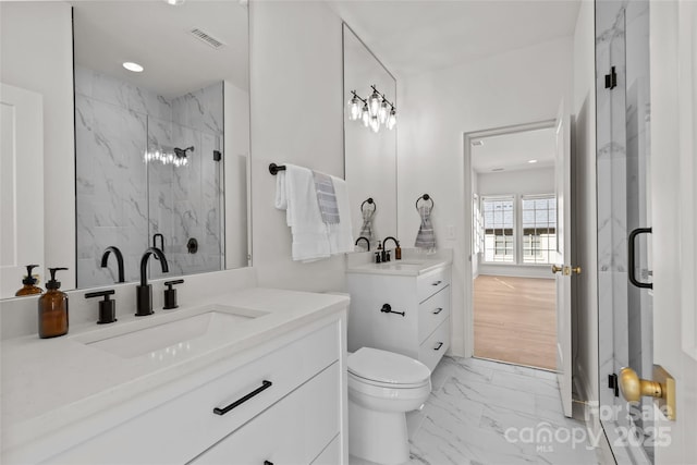 bathroom featuring a shower with door, vanity, and toilet