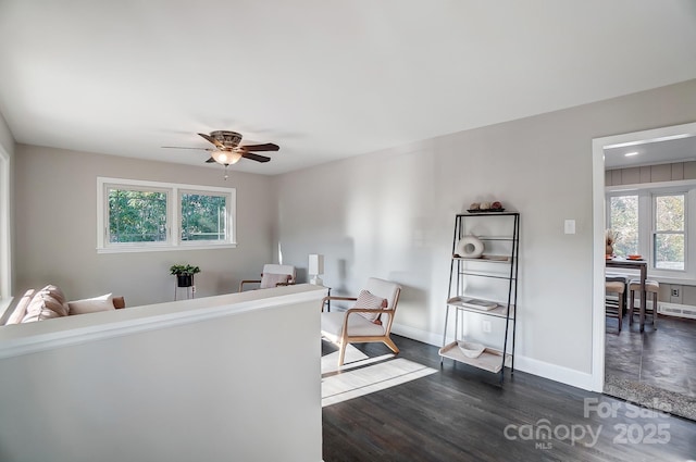 living room featuring ceiling fan, a healthy amount of sunlight, and dark hardwood / wood-style flooring