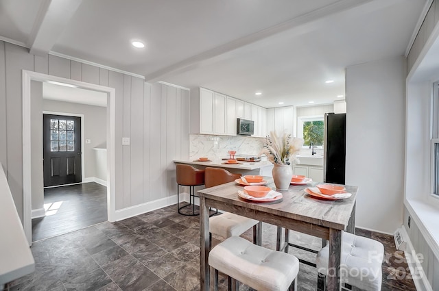 dining space featuring a healthy amount of sunlight, beam ceiling, and sink