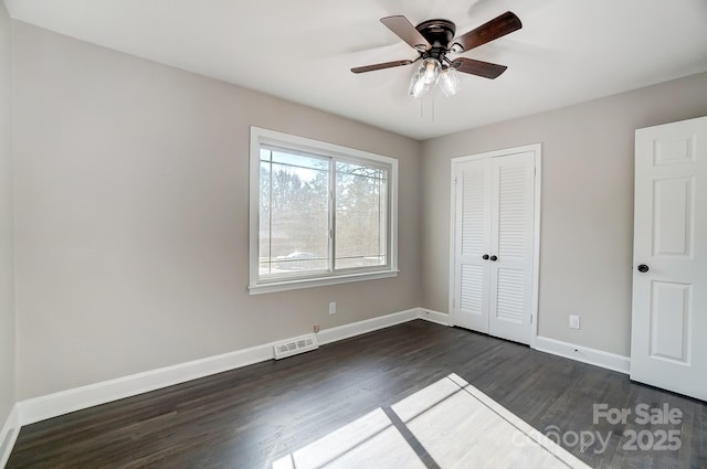 unfurnished bedroom with dark wood-type flooring, ceiling fan, and a closet