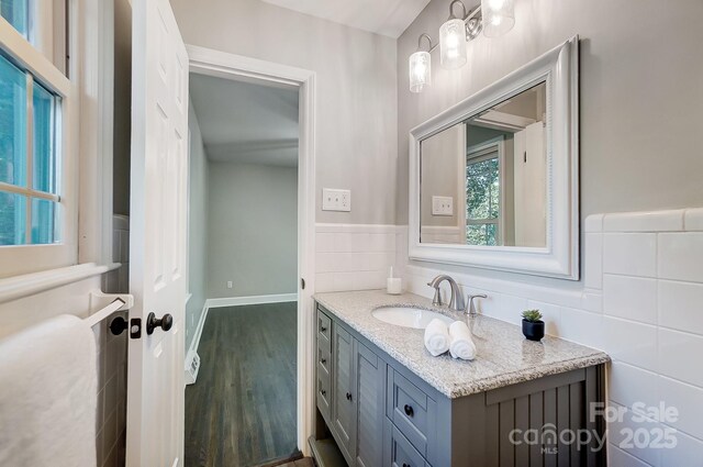 bathroom featuring vanity, hardwood / wood-style floors, and tile walls