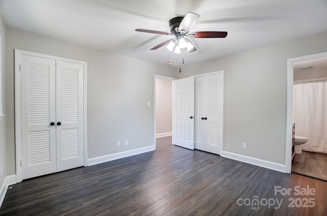 unfurnished bedroom with multiple closets, ensuite bathroom, dark hardwood / wood-style flooring, and ceiling fan