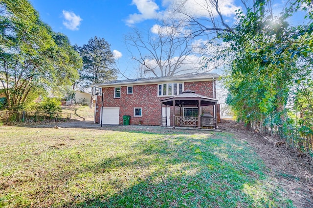 back of property with a gazebo, a garage, and a yard