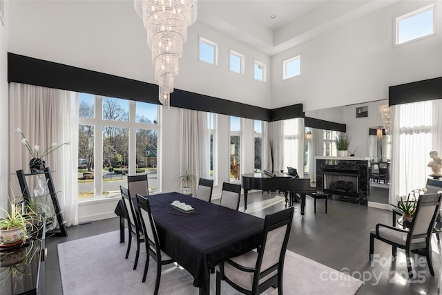 dining space featuring a premium fireplace, a towering ceiling, and an inviting chandelier