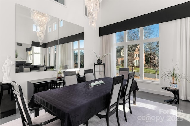 dining area featuring a healthy amount of sunlight, a high ceiling, and a notable chandelier