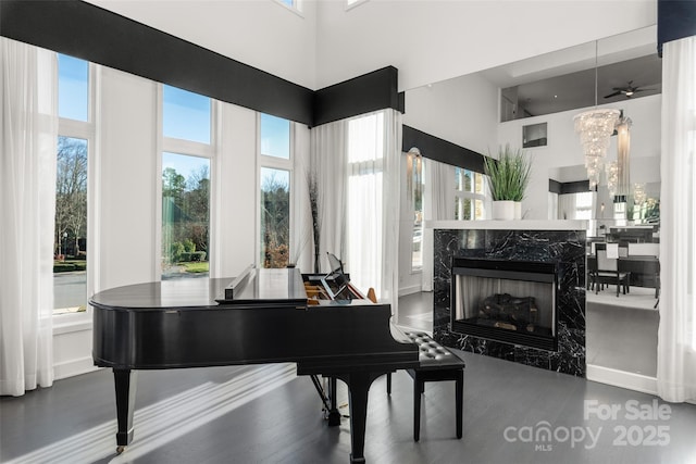 misc room featuring an inviting chandelier, a premium fireplace, and a high ceiling