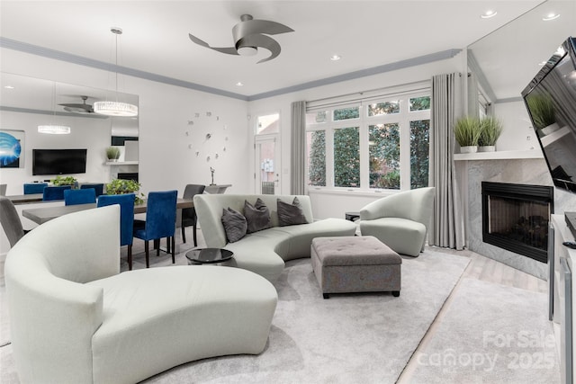 living room with crown molding, ceiling fan, a fireplace, and light hardwood / wood-style floors