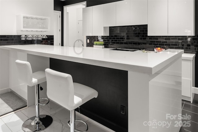 kitchen featuring decorative backsplash, white cabinets, and kitchen peninsula