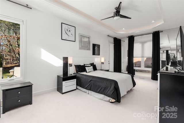 carpeted bedroom with multiple windows, a raised ceiling, and ceiling fan