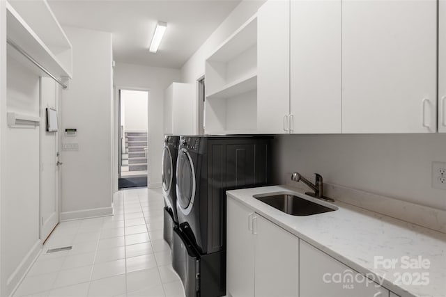 laundry area with light tile patterned flooring, cabinets, separate washer and dryer, and sink