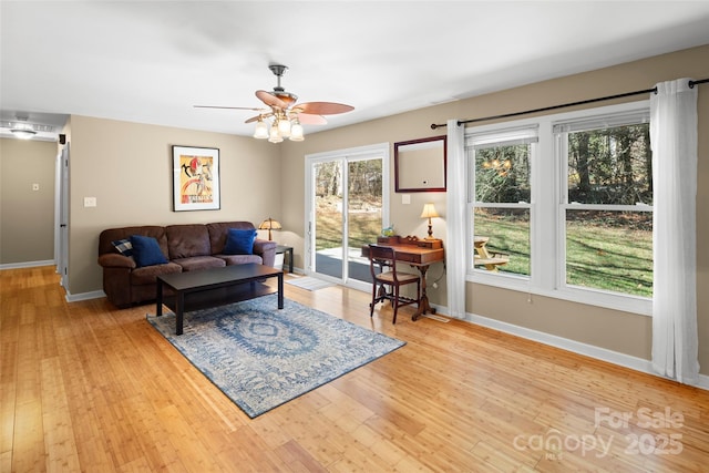 living room with ceiling fan, light wood-type flooring, and a healthy amount of sunlight