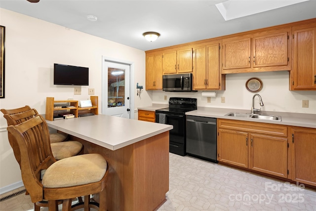 kitchen with sink, kitchen peninsula, a breakfast bar, and black appliances