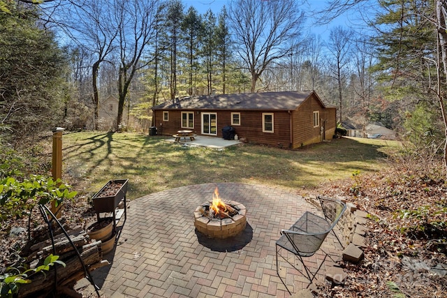 back of property featuring a yard, a patio area, an outdoor structure, and a fire pit