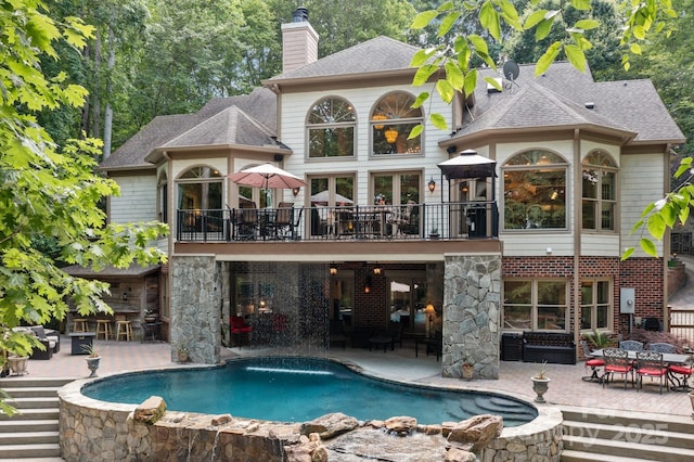 back of house with a balcony, a patio, and pool water feature