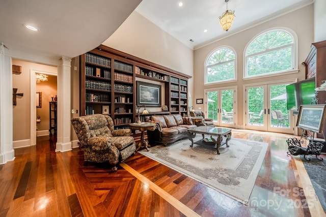 living room with a towering ceiling, dark wood-type flooring, french doors, and crown molding