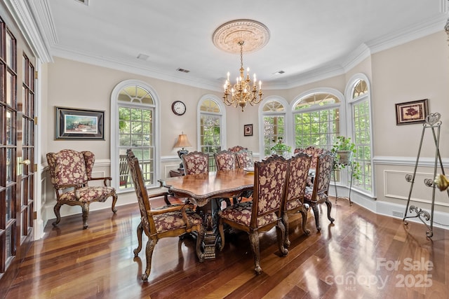 dining room featuring dark hardwood / wood-style flooring, ornamental molding, a notable chandelier, and a wealth of natural light