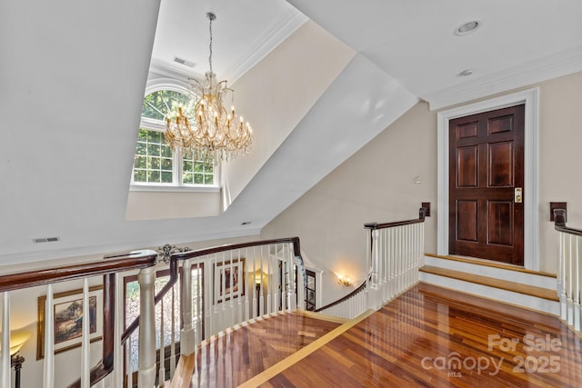 stairway featuring ornamental molding, an inviting chandelier, and hardwood / wood-style floors