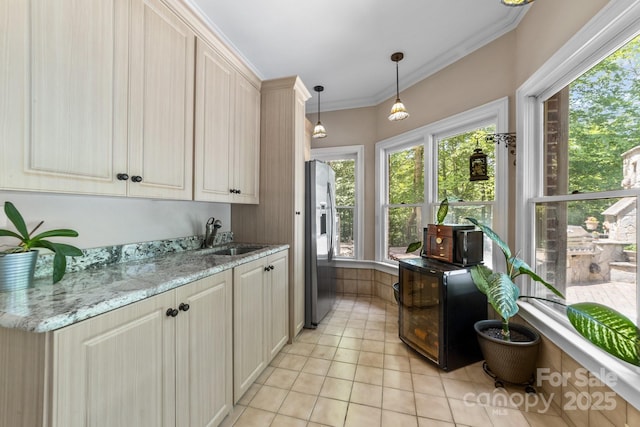 kitchen featuring light stone countertops, light tile patterned floors, stainless steel fridge, sink, and decorative light fixtures