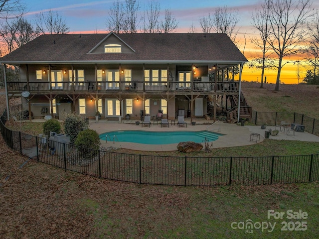 back house at dusk with a fenced in pool and a patio