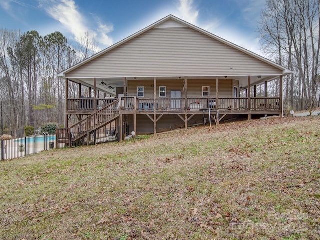 back of property with a yard, a fenced in pool, and ceiling fan