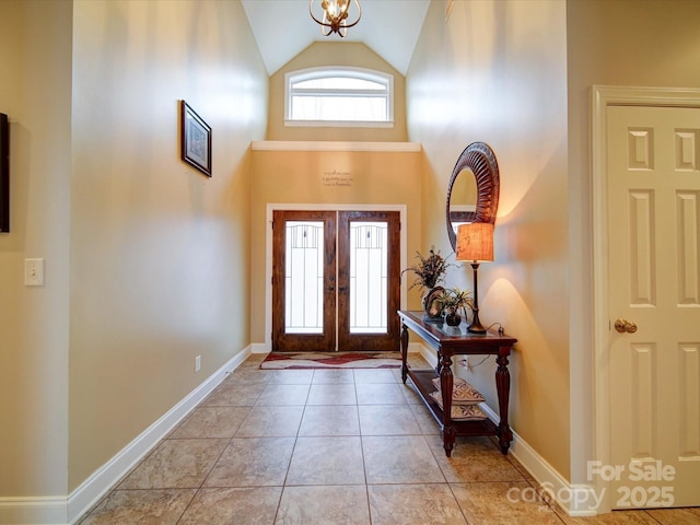 entryway with a chandelier, french doors, light tile patterned floors, and vaulted ceiling