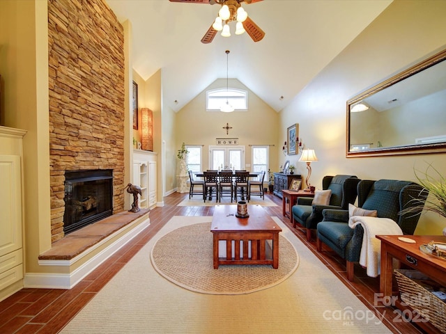 living room with high vaulted ceiling, hardwood / wood-style flooring, a stone fireplace, and ceiling fan