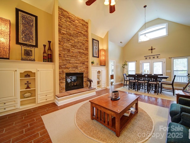 living room featuring ceiling fan, a fireplace, and a high ceiling