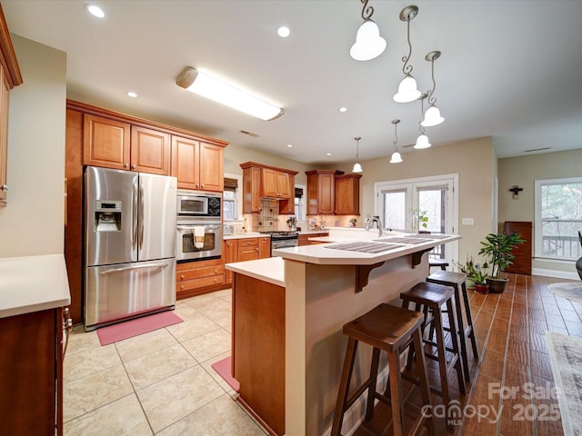 kitchen with appliances with stainless steel finishes, decorative light fixtures, plenty of natural light, and a breakfast bar area