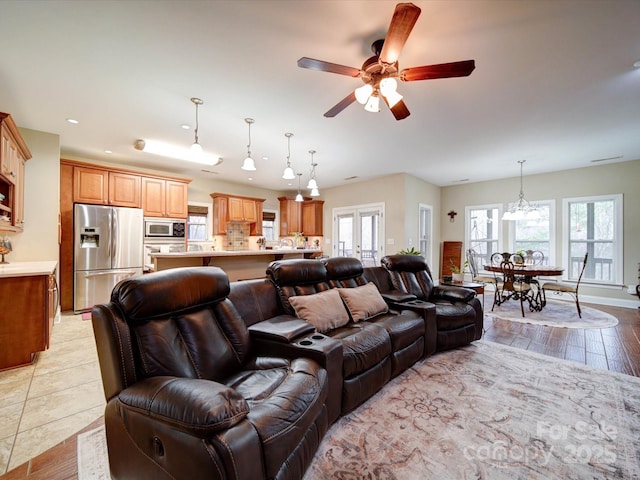 living room featuring ceiling fan with notable chandelier and light hardwood / wood-style floors