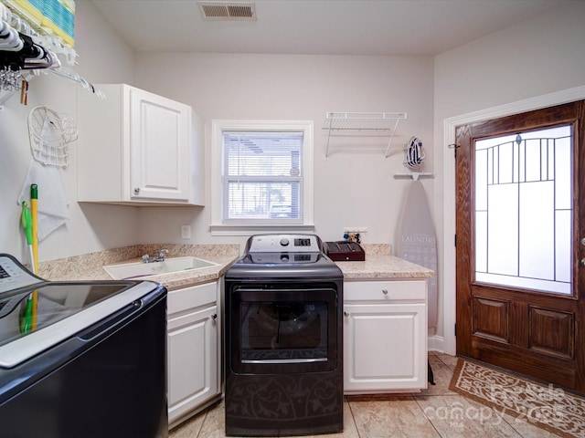 kitchen featuring light tile patterned flooring, white cabinetry, washer and dryer, and sink