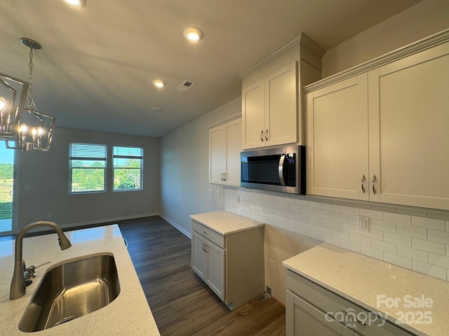 kitchen featuring decorative backsplash, light stone countertops, sink, and hanging light fixtures