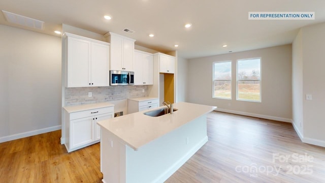 kitchen with white cabinetry, sink, and a kitchen island with sink