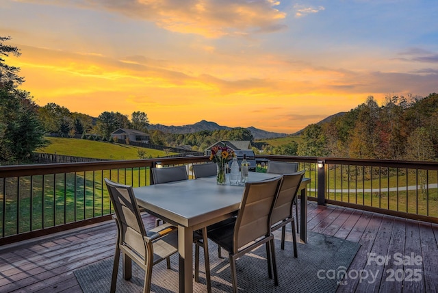 deck at dusk with a mountain view and a yard