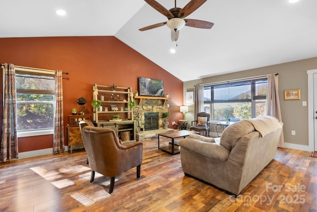 living room with ceiling fan, a fireplace, vaulted ceiling, and hardwood / wood-style flooring