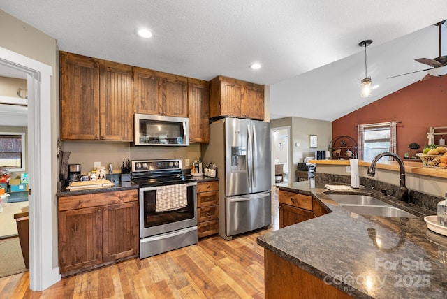 kitchen featuring appliances with stainless steel finishes, ceiling fan, sink, light hardwood / wood-style floors, and lofted ceiling