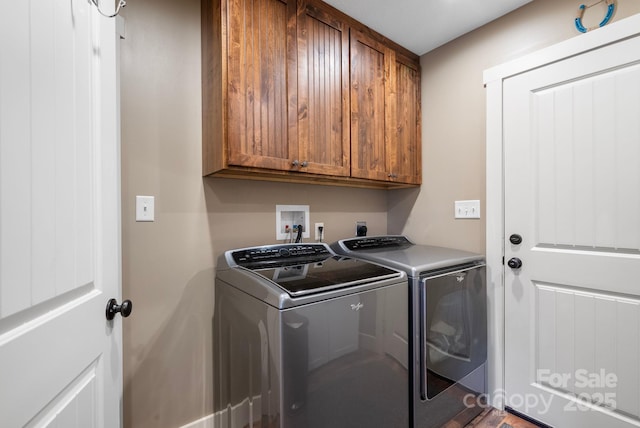 clothes washing area with cabinets and washing machine and dryer