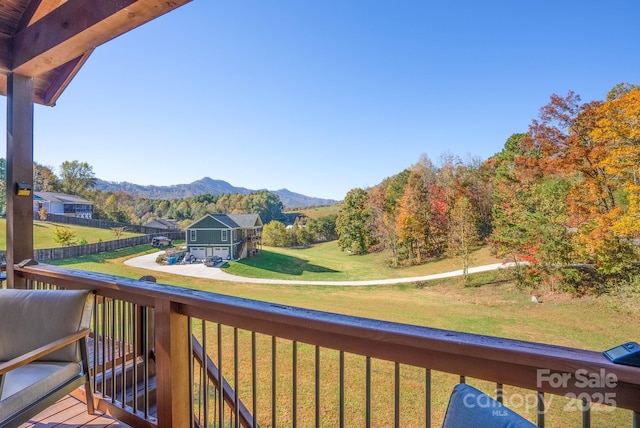 wooden deck featuring a mountain view and a lawn