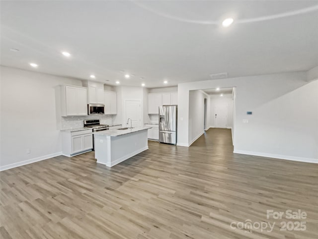 kitchen with backsplash, white cabinets, a center island with sink, sink, and appliances with stainless steel finishes