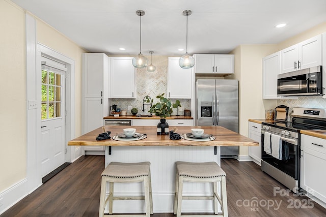 kitchen with white cabinetry, stainless steel appliances, and wood counters