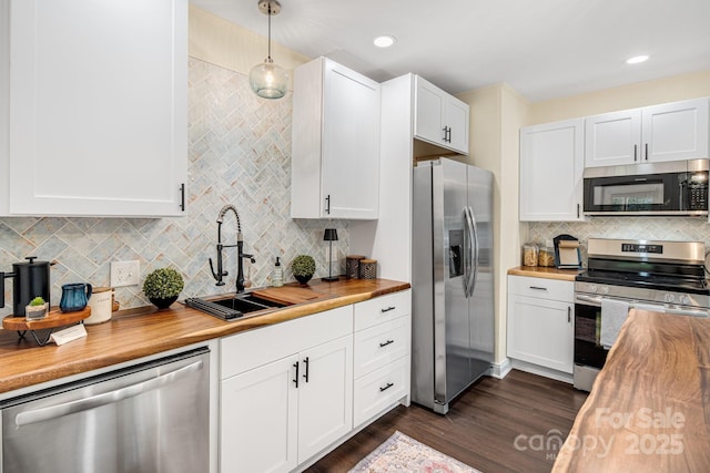 kitchen featuring wooden counters, appliances with stainless steel finishes, sink, pendant lighting, and white cabinetry