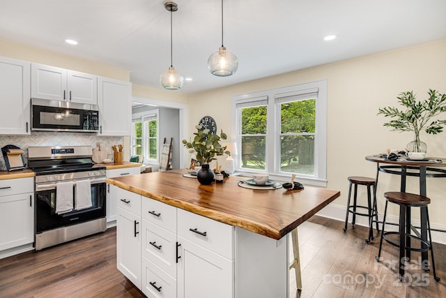 kitchen featuring white cabinetry, butcher block countertops, a breakfast bar area, a kitchen island, and appliances with stainless steel finishes