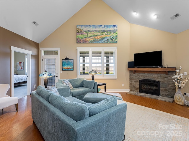 living room with a fireplace, high vaulted ceiling, and light wood-type flooring