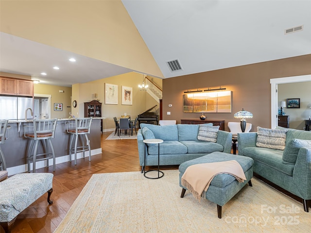 living room featuring light hardwood / wood-style flooring, high vaulted ceiling, and an inviting chandelier