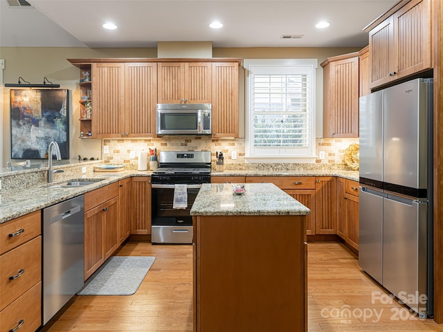 kitchen featuring a center island, light stone counters, sink, and appliances with stainless steel finishes