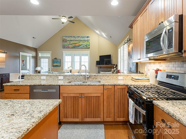 kitchen with lofted ceiling, sink, decorative backsplash, ceiling fan, and appliances with stainless steel finishes