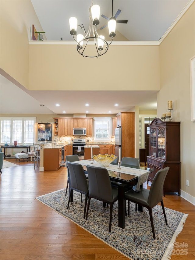 dining area featuring a high ceiling, sink, crown molding, light hardwood / wood-style floors, and a chandelier