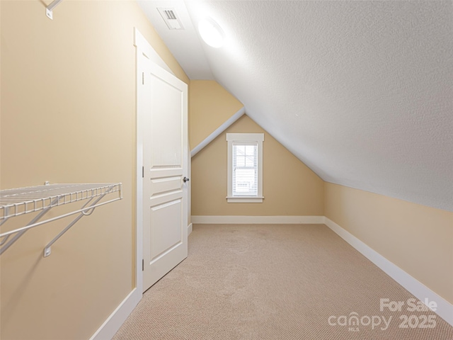 bonus room with vaulted ceiling, light carpet, and a textured ceiling