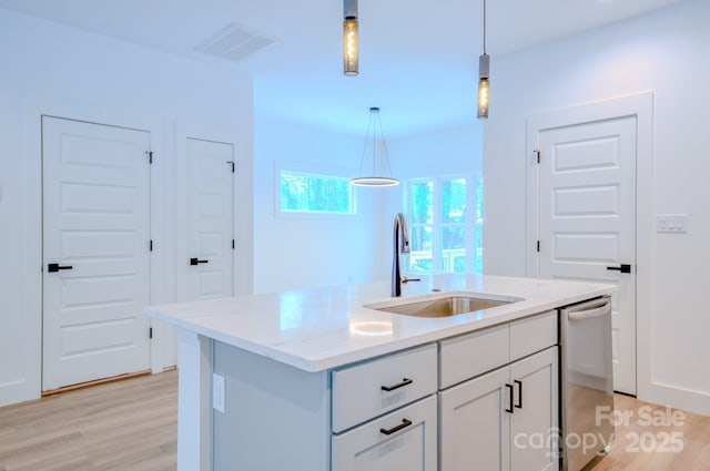 kitchen featuring a center island with sink, dishwasher, sink, and hanging light fixtures